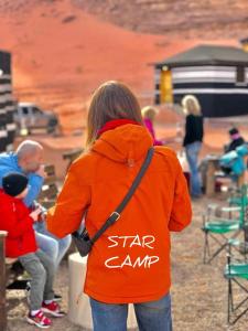 Una donna con una camicia arancione in piedi con un bambino di STAR CAMP & WiTH TOR a Wadi Rum