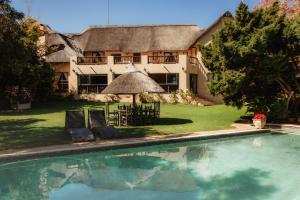a house with a pool and two chairs in front of it at Blue Hills Lodge in Midrand