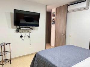 a bedroom with a bed and a flat screen tv on the wall at Cómodo Apartamento en el sur de Cali in Cali
