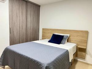 a bedroom with a bed with a blue pillow on it at Cómodo Apartamento en el sur de Cali in Cali