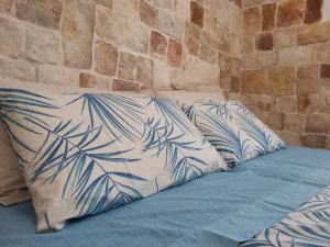 1 cama con almohadas azules y blancas junto a una pared en Villa Su Monte Abele, en Selva di Fasano