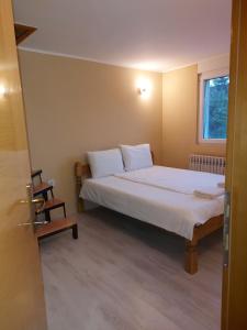 Schlafzimmer mit einem Bett mit weißer Bettwäsche und einem Fenster in der Unterkunft Vikendica Nika in Palić