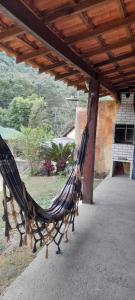 a hammock sitting under a roof on a patio at Casa girassol in Nova Friburgo