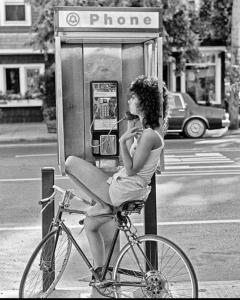 Kobieta siedząca przy budce telefonicznej na rowerze w obiekcie Rynek Pokoje Paris -Parking w Kielcach