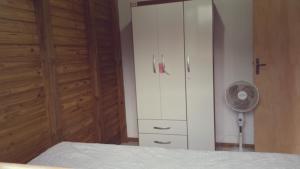 a bedroom with a white cabinet and a fan at Casa De Praia Galheta in Farol de Santa Marta