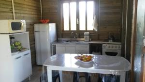 a kitchen with a table with a bowl of fruit on it at Casa De Praia Galheta in Farol de Santa Marta +17 photos
