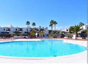 a large swimming pool in a resort with palm trees at Apartamento Casa el Canario in Costa Teguise