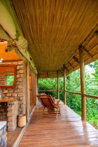 un porche de una cabaña con una silla en Sharp Island Gorilla Lodge, Lake Bunyonyi, en Kashasha