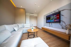 a living room with a couch and a tv on a wall at Absolute Hotel Ksamil in Ksamil