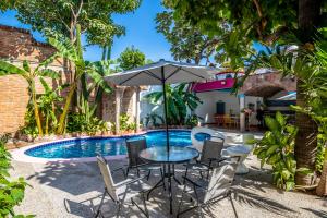 - une table avec un parasol à côté de la piscine dans l'établissement Charming Colonial Mexican Hacienda, à Puerto Vallarta