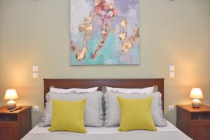 a bedroom with a bed with yellow pillows and a painting at Casa Vyron in Ipsos