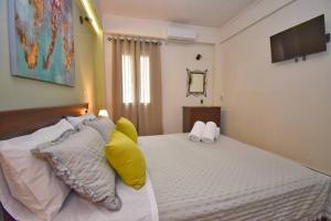 a bedroom with a bed with yellow and white pillows at Casa Vyron in Ipsos +23 photos