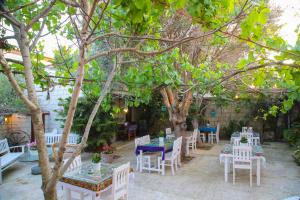 un patio con mesas blancas y sillas bajo un árbol en Alaçatı Kavalalı Otel, en Alacati