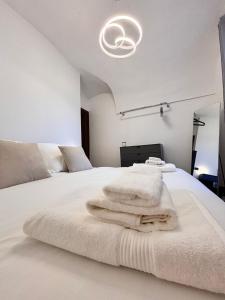 una camera da letto con un letto bianco e asciugamani di Casa Jolie - vista castello a Dolceacqua