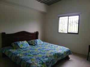 1 dormitorio con 1 cama con edredón azul y ventana en Shammah-casa de descanso en Valledupar