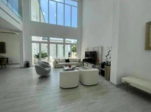 uma grande sala de estar com mobiliário branco e janelas grandes em Alojamiento en Samborondon em Guayaquil