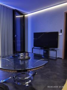 un soggiorno con tavolo in vetro e TV a schermo piatto di Ferienwohnung Jessica a Mastershausen