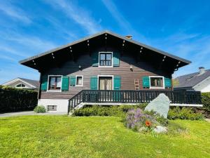 a house with a black roof and a yard at Chalet entre lac et montagnes in Lugrin