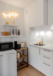 eine weiße Küche mit einer Spüle und einer Mikrowelle in der Unterkunft Studio lumineux à 2 mn à pied de la plage in Cannes