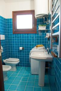 a blue tiled bathroom with a sink and a toilet at Villa Angedras in San Teodoro +13 photos