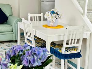 een witte tafel met 2 stoelen en paarse bloemen bij Blue Apartment in Ischia