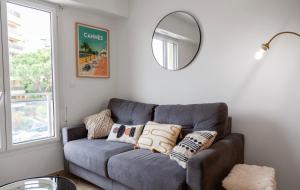 un sofá gris en una sala de estar con espejo en Studio lumineux à 2 mn à pied de la plage en Cannes
