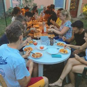 a group of people sitting around a table eating food at Budapest Garden Hostel in Budapest
