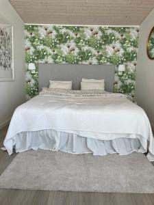 谢尔港Eget gästhus i västkustpärlan Skärhamn的卧室里有一张白色的床，墙上挂着花