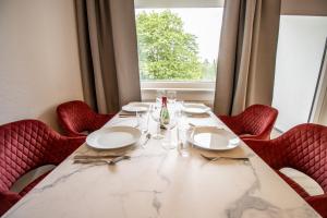 einen Tisch mit roten Stühlen und ein großes Fenster in der Unterkunft Messe-Apartment für 5 Gäste mit Balkon und Lift in Hannover