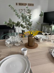 una mesa con copas de vino y un jarrón con una planta en Casa Nella, centre et parking, madamedemconciergerie, en Reims