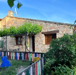a stone house with a colorful fence in front of it at Casa del Espliego in Barriopedro