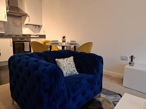 ein blaues Sofa im Wohnzimmer mit einem Tisch in der Unterkunft Stunning Station Apartment in Kent