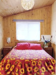 um quarto com uma cama com um edredão vermelho e uma janela em "PINARES DEL MAR" Pequeñas cabañas ECO rusticas sello "S" em Isla Negra