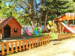 un patio trasero con un patio de juegos con una casa de juegos y un parque infantil en "PINARES DEL MAR" Pequeñas cabañas ECO rusticas sello "S", en Isla Negra