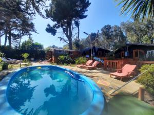 a swimming pool in a yard with a house at "PINARES DEL MAR" Pequeñas cabañas ECO rusticas sello "S" in Isla Negra