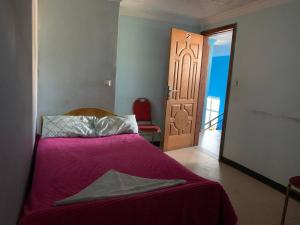 1 dormitorio con 1 cama con manta morada y puerta en AM Guest House en Kitimē