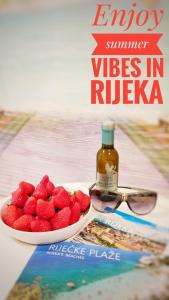 a bowl of strawberries and a bottle of wine and glasses at Center Rooms with terrace in Rijeka