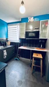 a kitchen with blue walls and a counter and a table at Chambre Privée Kozy - Stade de France in Saint-Denis