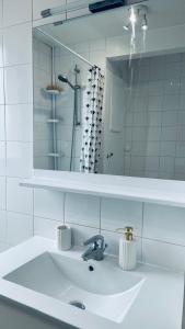 ein weißes Badezimmer mit einem Waschbecken und einem Spiegel in der Unterkunft Chambre Privée Kozy - Stade de France in Saint-Denis
