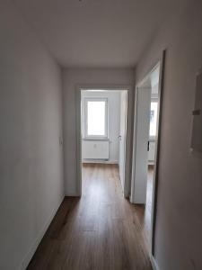 um quarto vazio com uma janela e um piso de madeira em Beste Apartments em Meerane