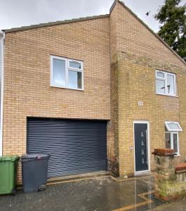 een bakstenen gebouw met een garagedeur en twee ramen bij Roomello luxury City Studios in Peterborough