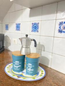 una macchinetta del caffè e due secchi su un piatto su un bancone della cucina di Tiffany Holiday Home a Ischia