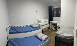um pequeno quarto com duas camas e uma escrivaninha em CASA FAMILIAR “SANTA PAZ” 2 em Aparecida