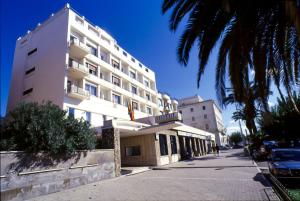 a tall white building with a palm tree in front of it at Hotel Mediterraneo in Civitavecchia