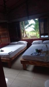 2 camas en una habitación con ventana en Cabañas Zona Verde, en Nuquí