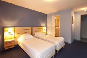 Dos camas en una habitación de hotel con sábanas blancas. en Villa Mariale by Popinns, en Lourdes