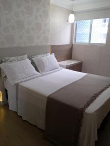 a bedroom with a large white bed and a window at APARTAMENTO LUXUOSO A 1KM DA LITORÂNEA in São Luís