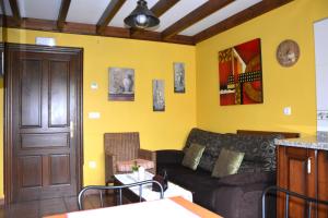 - un salon avec un canapé et des murs jaunes dans l'établissement Apartamentos Rurales Piedrafita, à Llenín