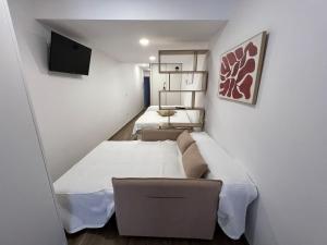 une petite chambre avec deux lits et un canapé dans l'établissement White House, Castellón de la Plana