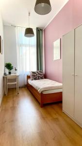 um quarto com uma cama e uma parede rosa em Beautiful rooms in the center em Szczecin